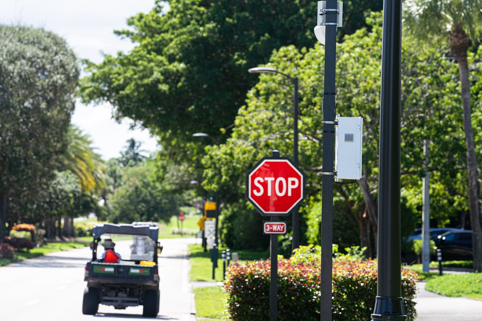 Pole-mounted HOA Safety camera beside a stop sign on a community road